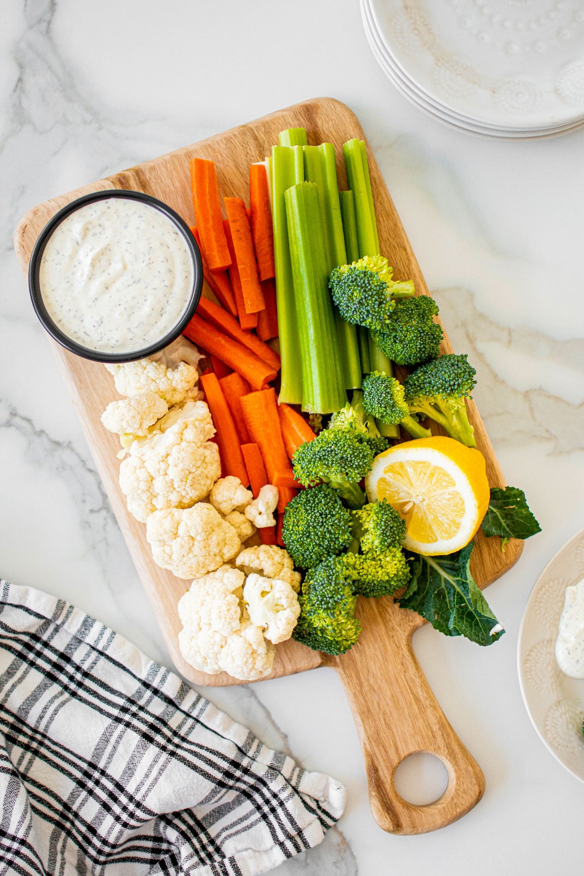 organic dill dip with sour cream in a bowl on a veggie platter on a marble countertop.
