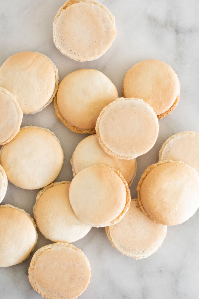 baked chocolate malt french macarons on a marble counter.