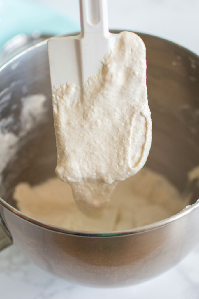 french macaron batter being stirred with a spatula in a mixing bowl.
