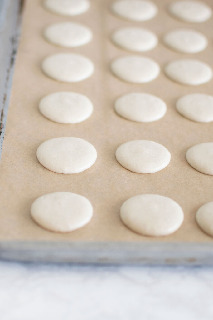 french macarons after banging on a baking sheet on a marble counter.