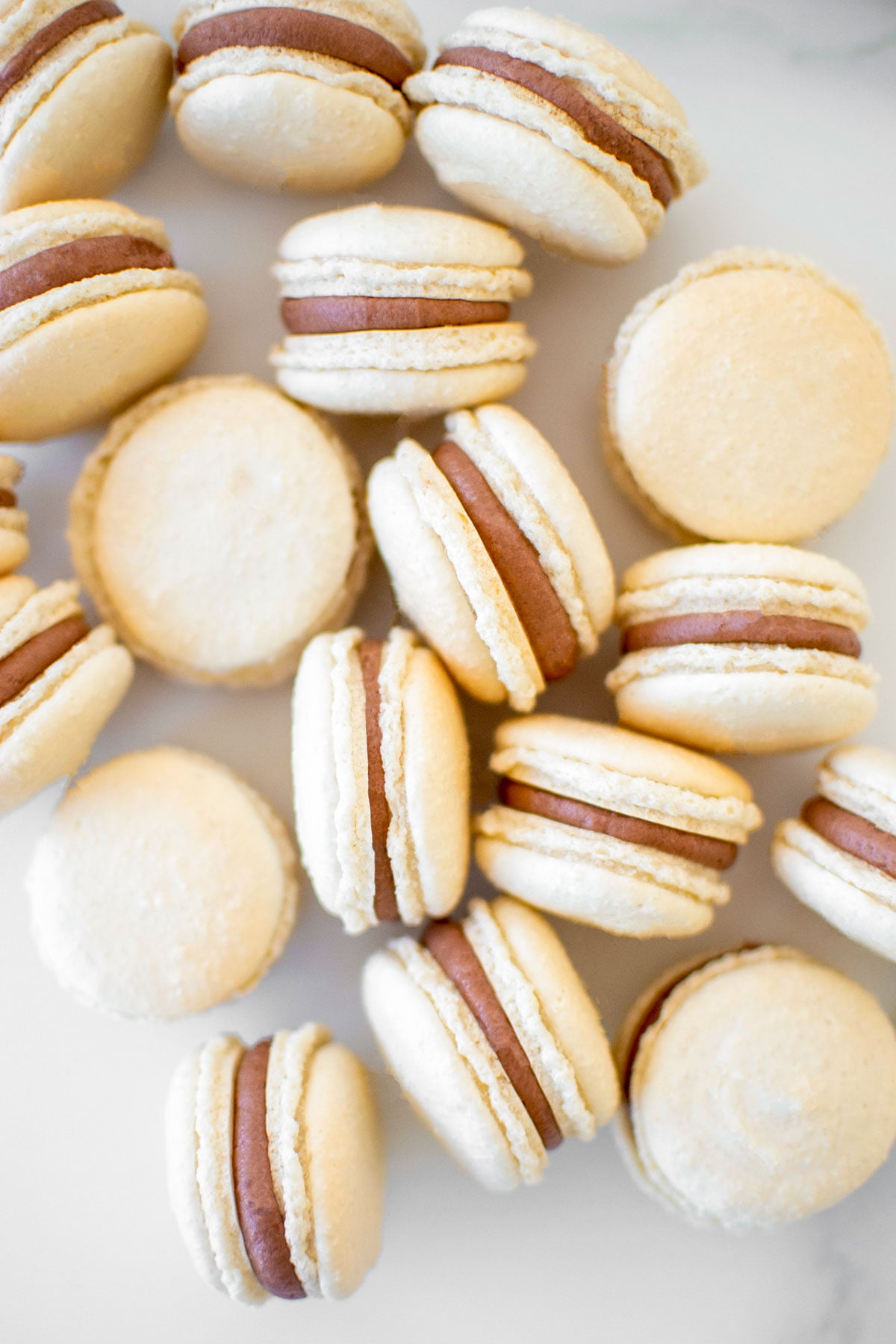chocolate malt french macarons on a marble counter.