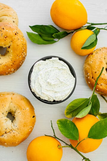 dill cream cheese spread in a bowl with fresh lemons and bagels around it.