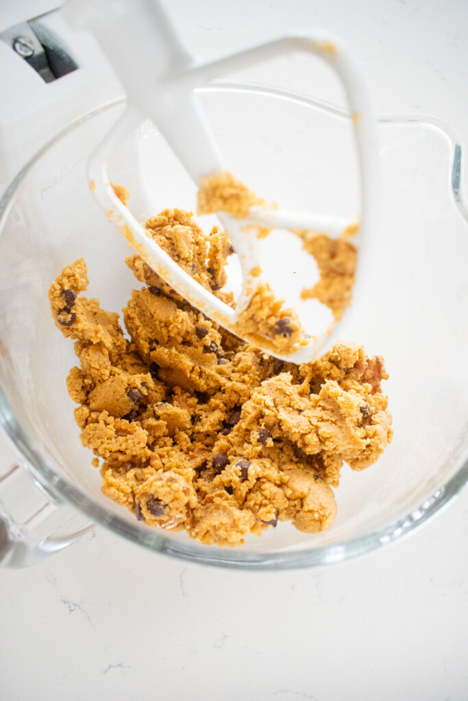glass mixing bowl with kamut flour chocolate chip cookie dough on a marble counter.