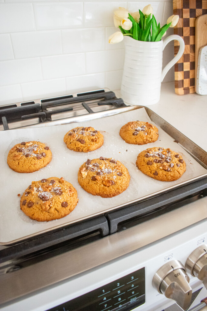 baked kamut flour chocolate chip cookies on a baking sheet cooling on top of an oven.