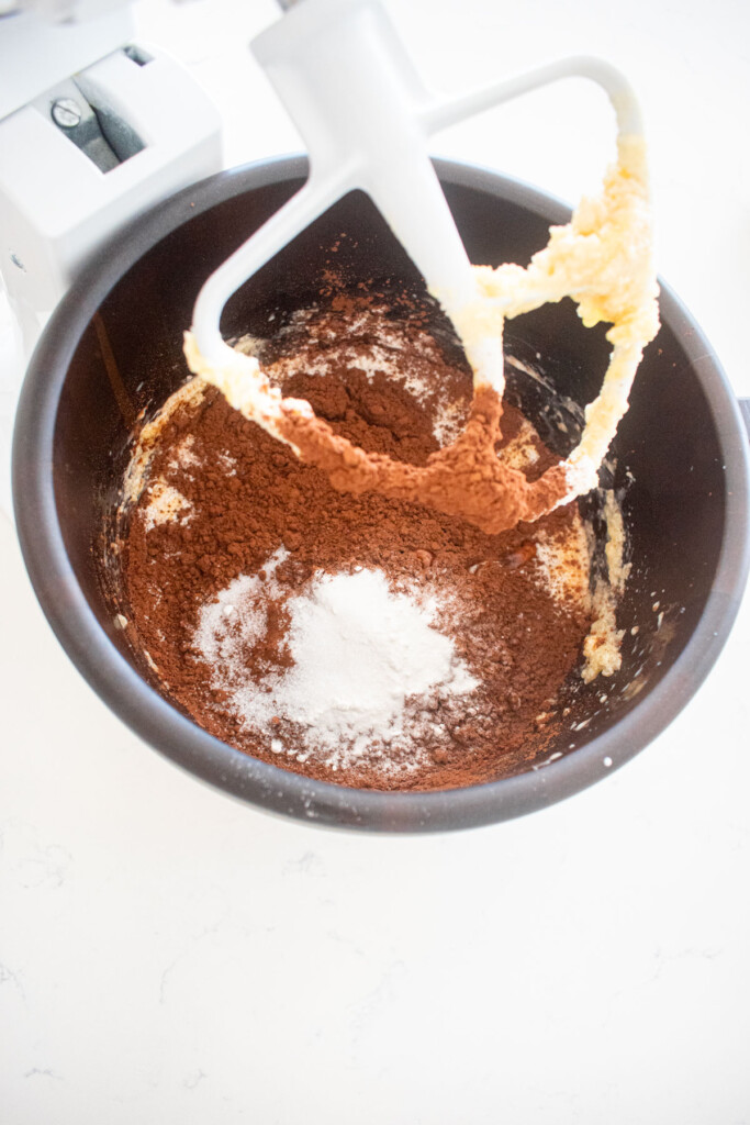 dry ingredients added to wet ingredients in a wood mixing bowl on a marble counter.
