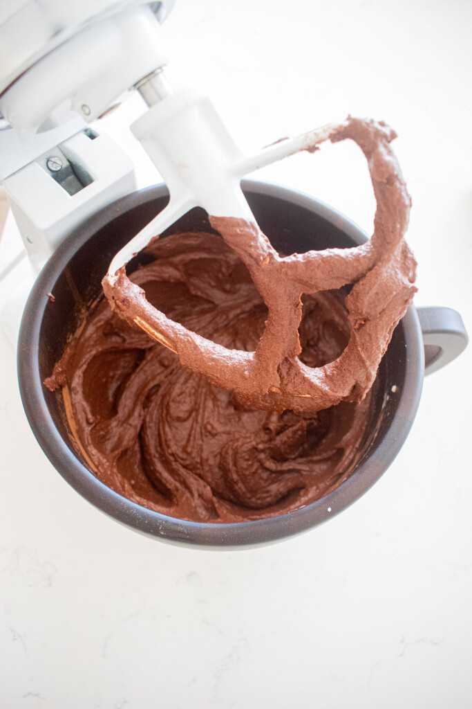 chocolate cake batter in a wood mixing bowl on a marble counter.