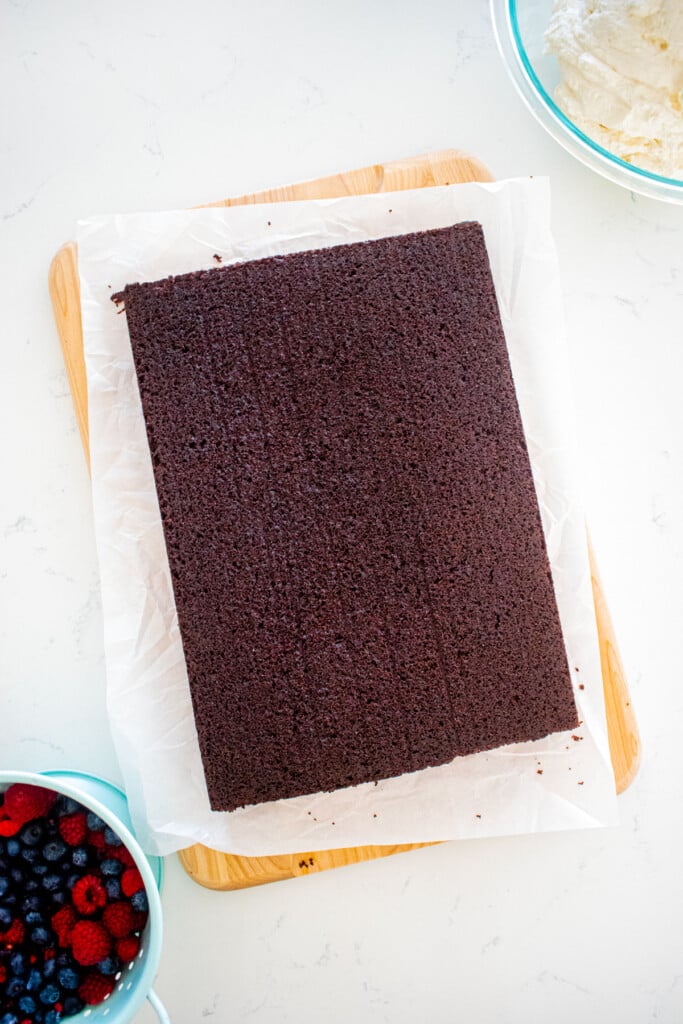 baked chocolate sheet cake on a wood serving board on a marble counter.