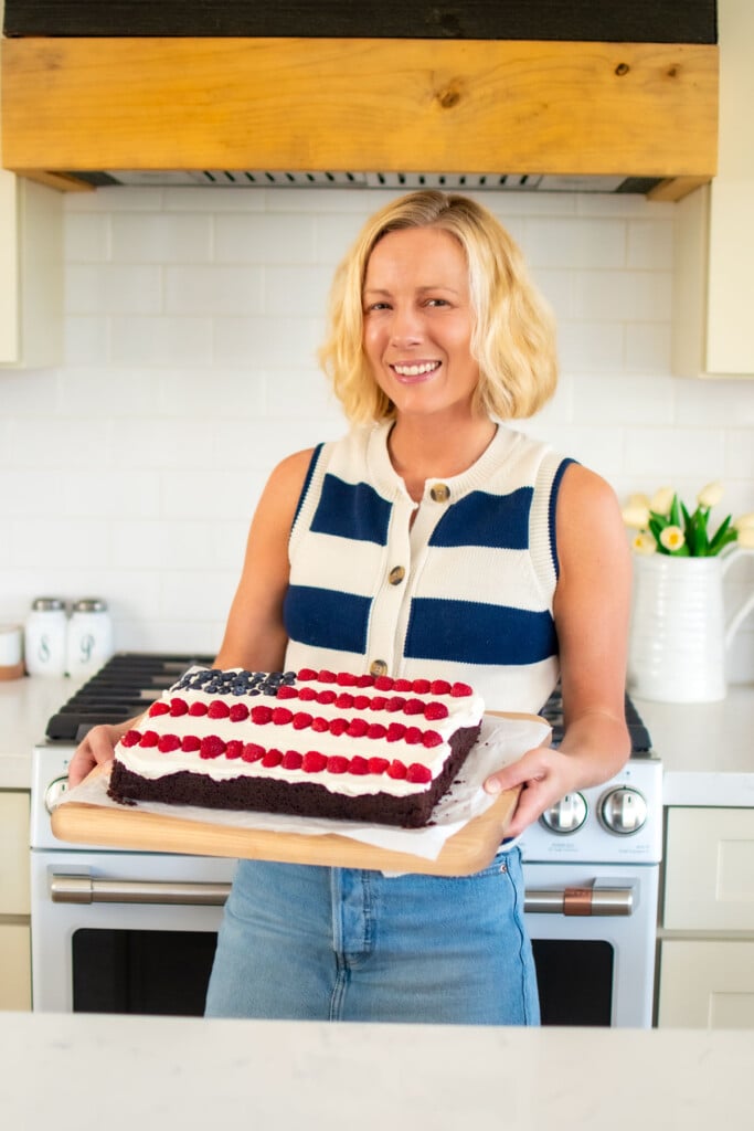 woman holding a chocolate berry flag cake in the kitchen.