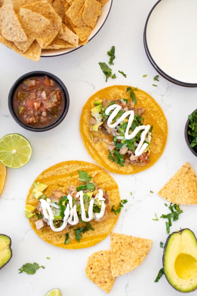 garlic lime chicken street tacos being assembled on a marble countertop.