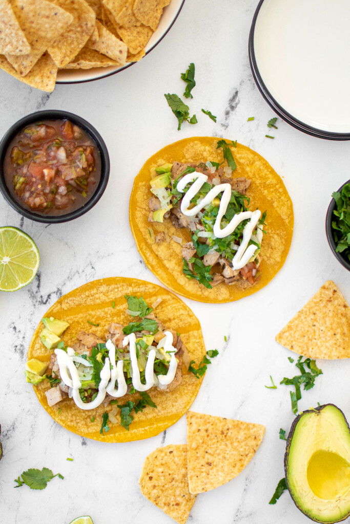 garlic lime chicken street tacos being assembled on a white marble countertop.
