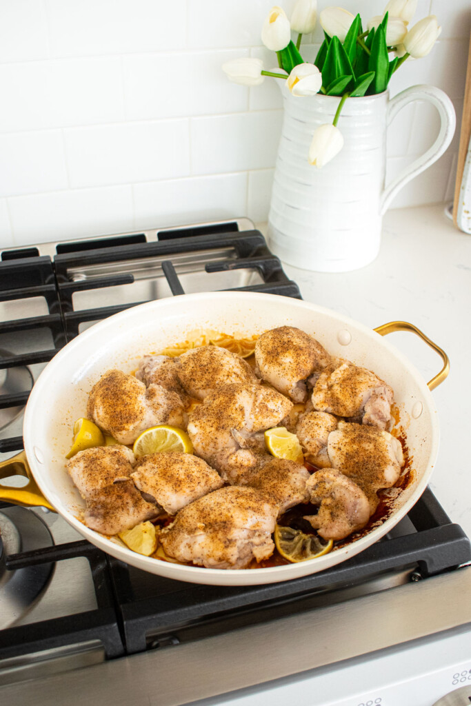 cooked chicken thighs with taco seasoning and limes in a skillet over the stovetop.