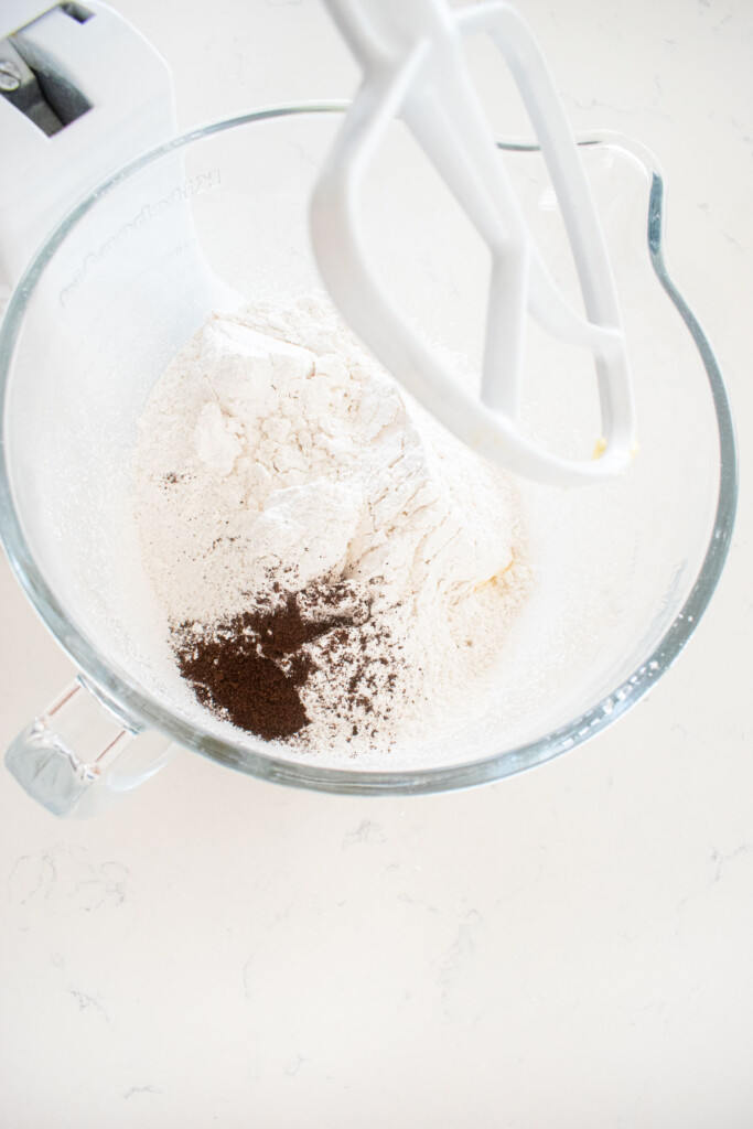 ingredients for vanilla bean buttercream frosting in a glass stand mixing bowl on a white marble counter.