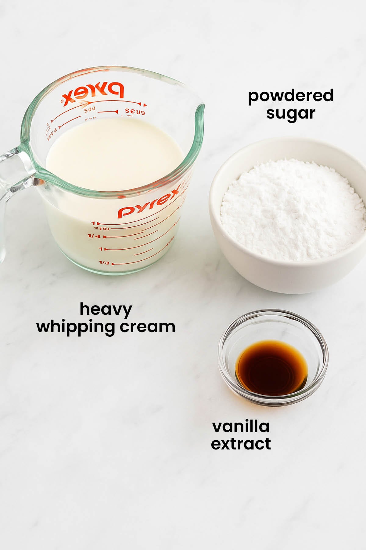 individual ingredients for homemade whipped cream frosting laid out against a white background.