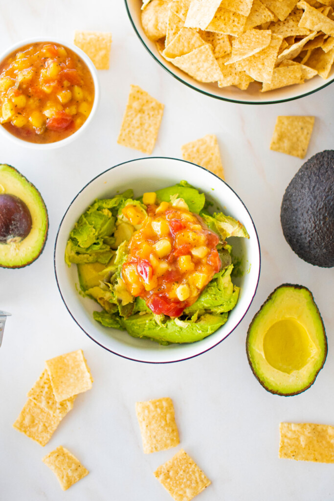 avocado, lime and mango salsa in a bowl on a marble countertop.