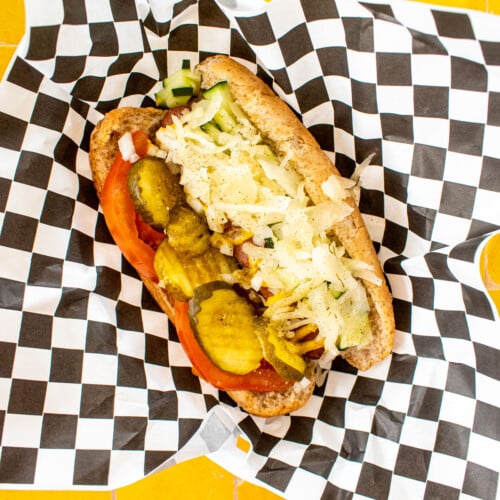 organic chicago style hot dog with sauerkraut in a basket with a black and white checkered paper.