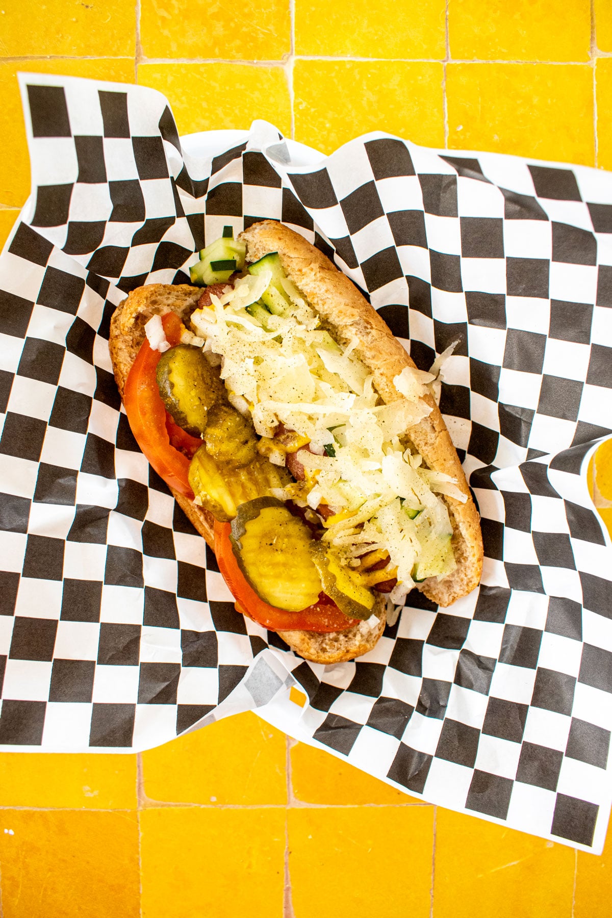 organic chicago style hot dog with sauerkraut in a basket with a black and white checkered paper.