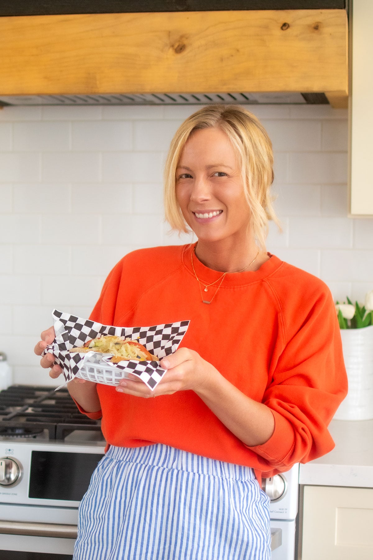 woman holding a basket with an organic chicago style hot dog with sauerkraut.