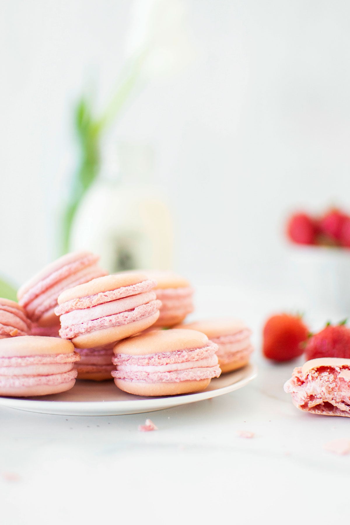 plate of strawberry french macarons on a marble counter with fresh strawberries.