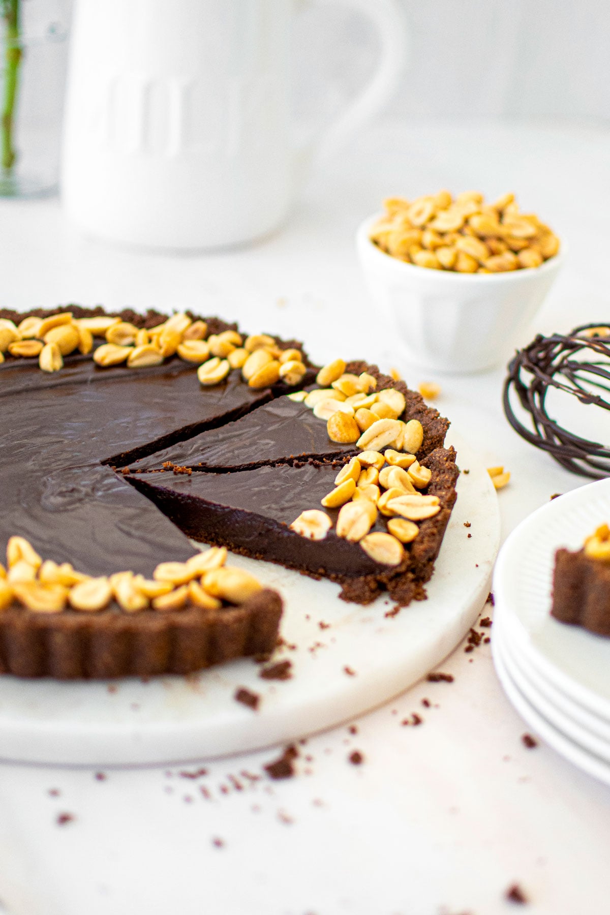 chocolate peanut butter tart with chocolate graham cracker crust cut into slices on a marble serving board.