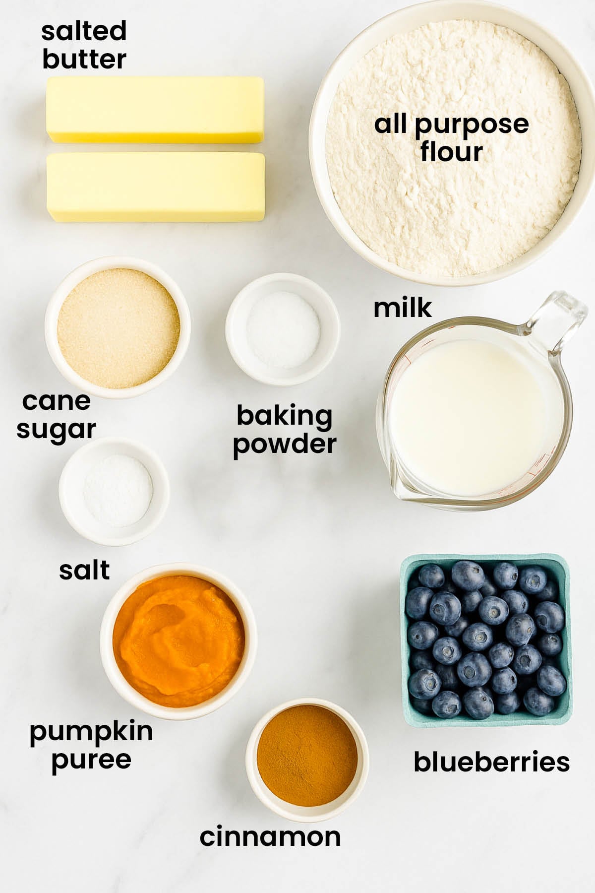 individual ingredients for homemade blueberry waffles without eggs laid out against a white background.