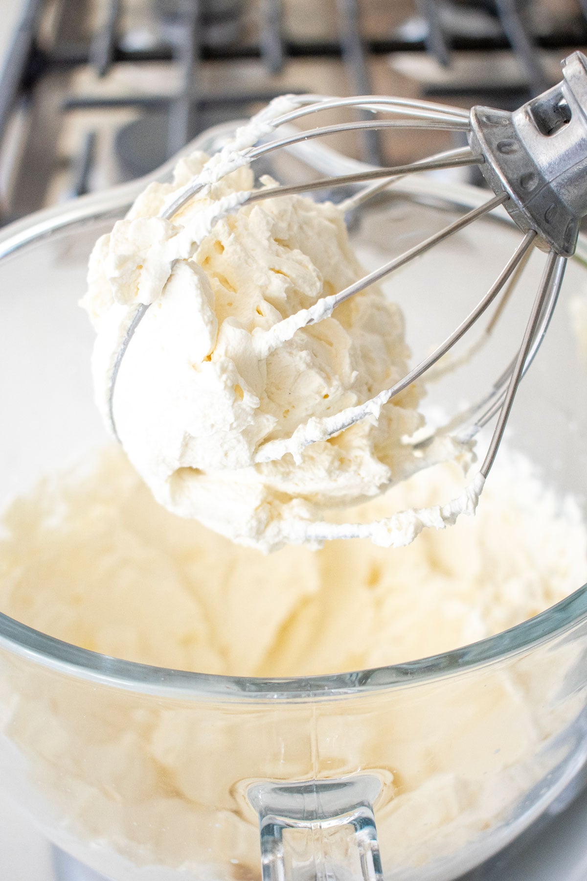 homemade organic whipped cream whipped into stiff peaks in a glass mixing bowl.