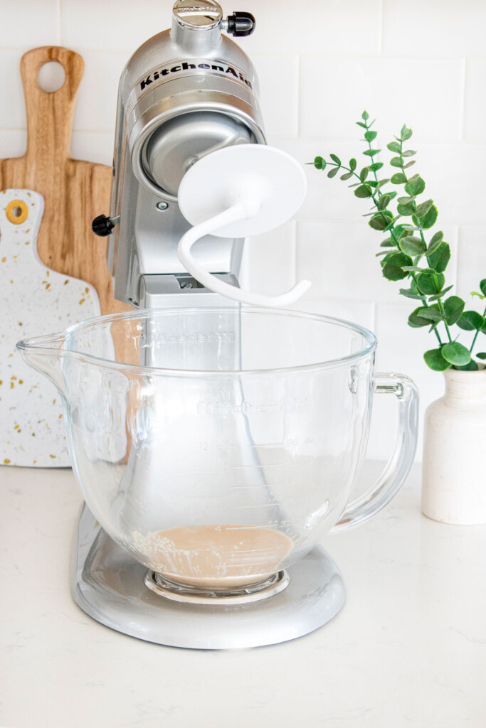 yeast in a glass mixing bowl on a white kitchen countertop.