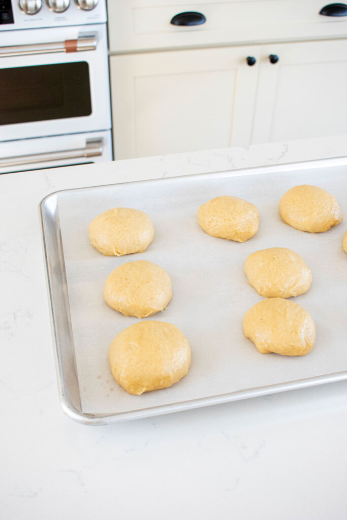 organic brioche buns dough rising on a baking sheet.