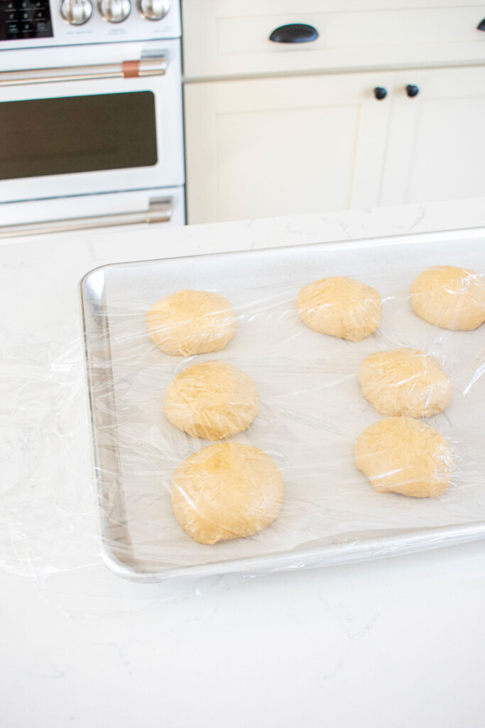 organic brioche buns dough rising on a baking sheet.