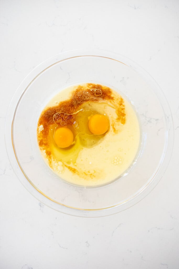 wet ingredients for chocolate cake in a glass mixing bowl on a white marble counter.