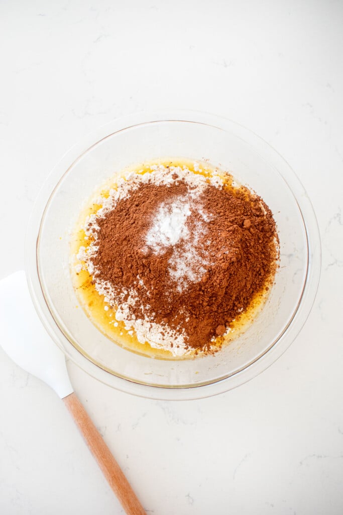 ingredients for cherry cake in a glass mixing bowl on a white marble counter.
