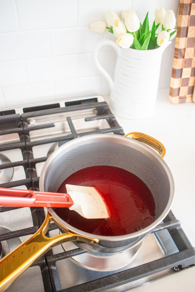 homemade cherry marshmallow ingredients being stirred in a pot over the stovetop.