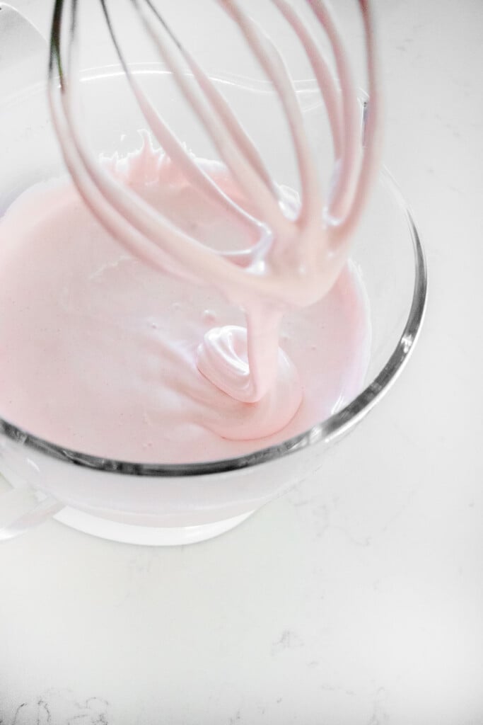 homemade cherry marshmallows in a glass mixing bowl on a white marble counter.