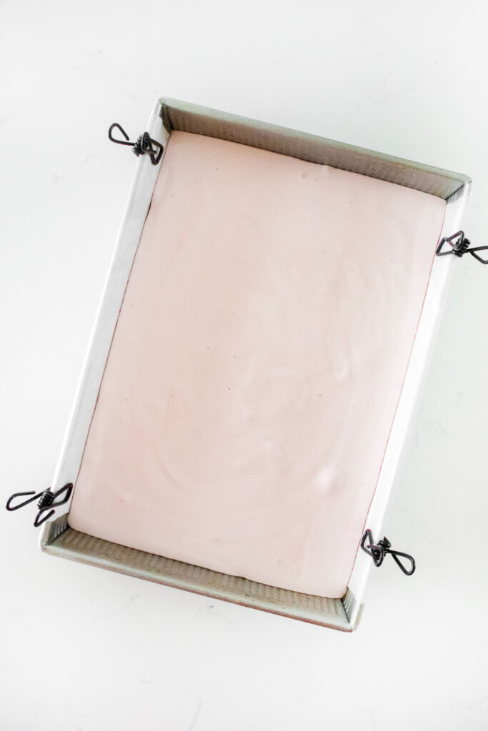 homemade cherry marshmallows in a baking pan on a white marble counter.