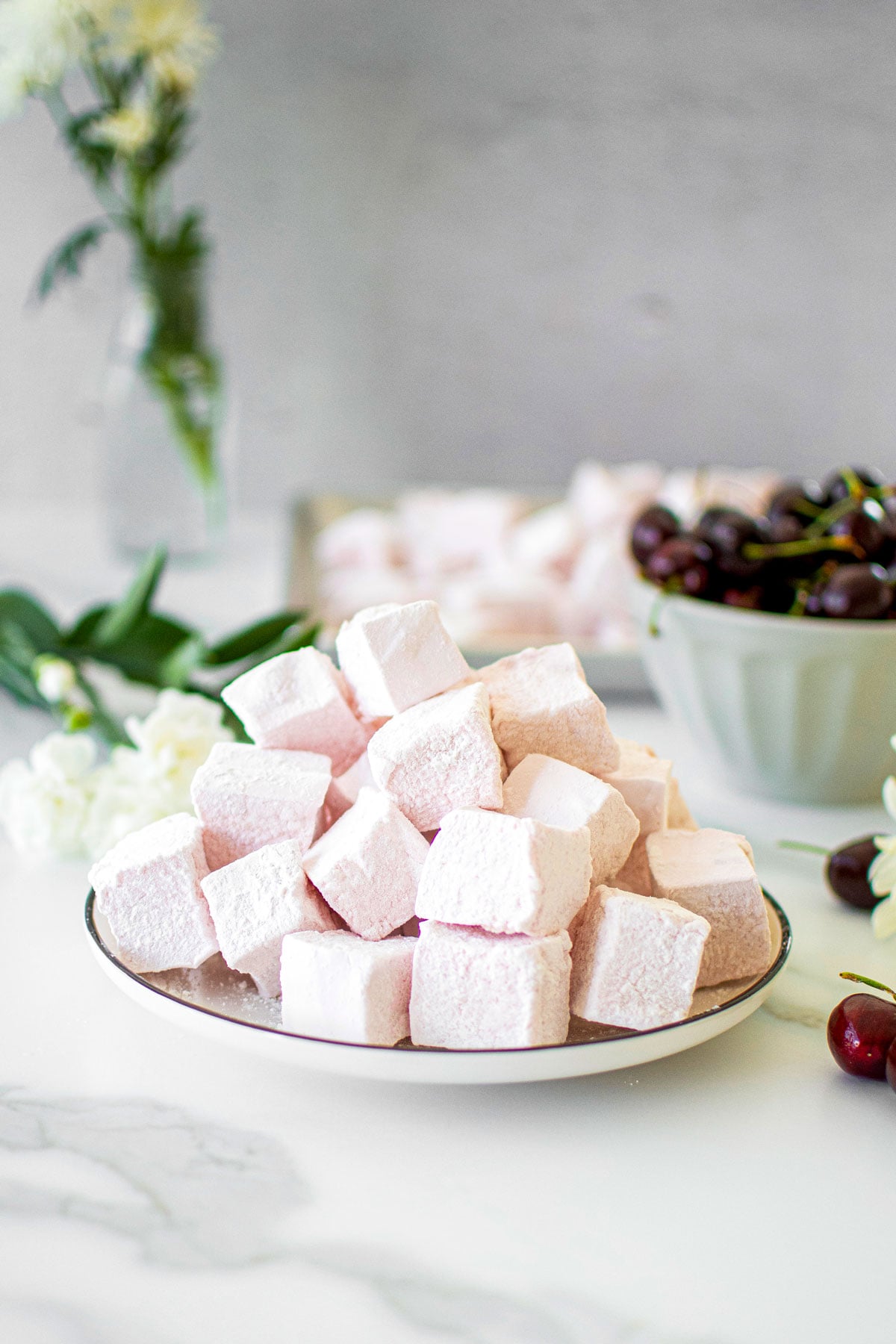 plate of homemade cherry marshmallows on a white marble counter.
