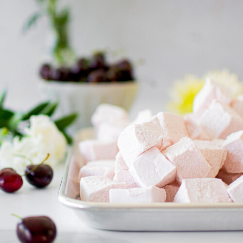 homemade cherry marshmallows on a baking sheet on a marble counter.