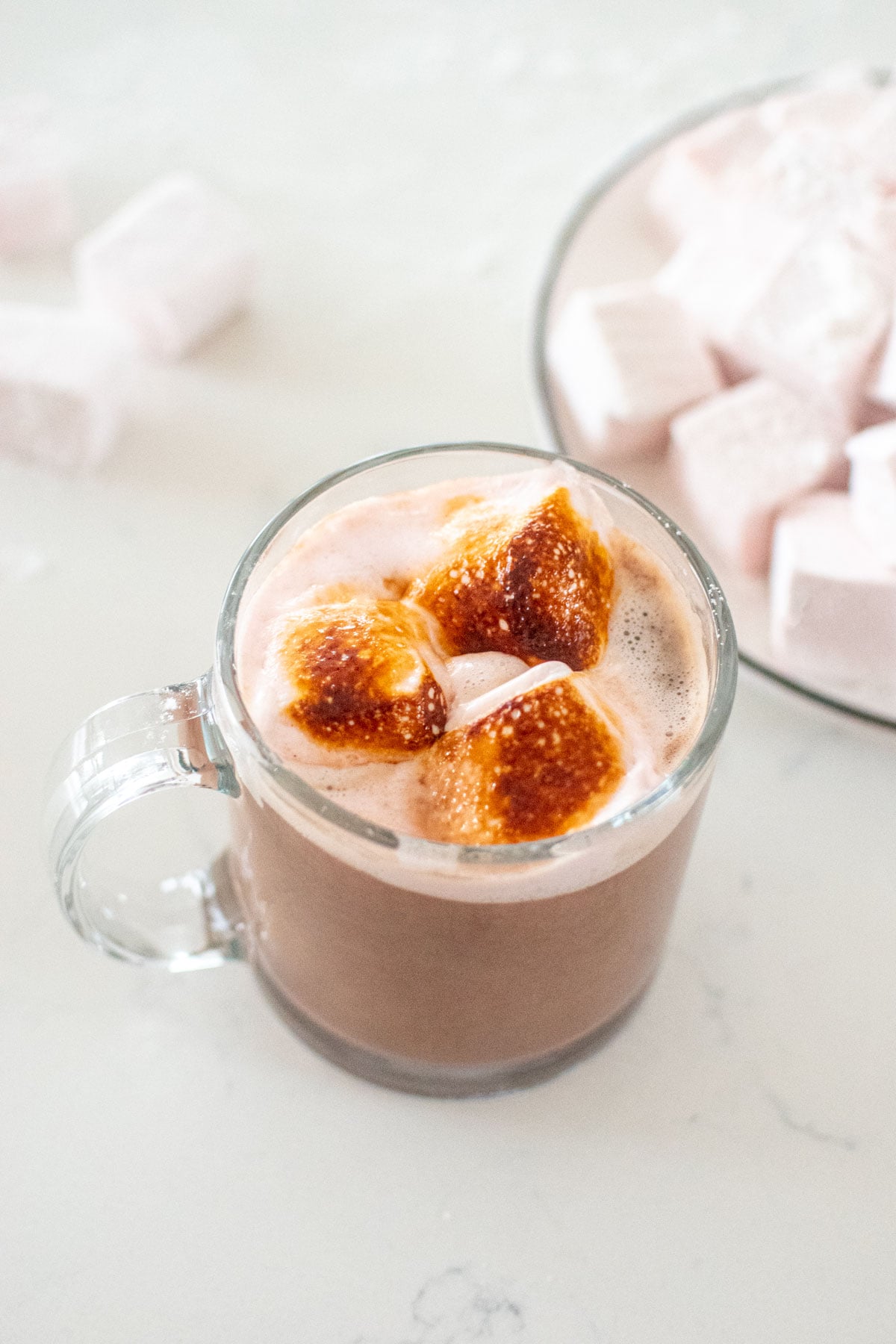 mini cherry marshmallows torched in hot chocolate on a white marble counter.