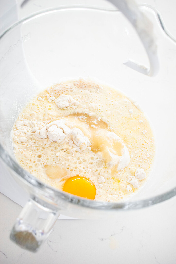ingredients for one rise cinnamon rolls in a glass mixing bowl on a white marble counter.