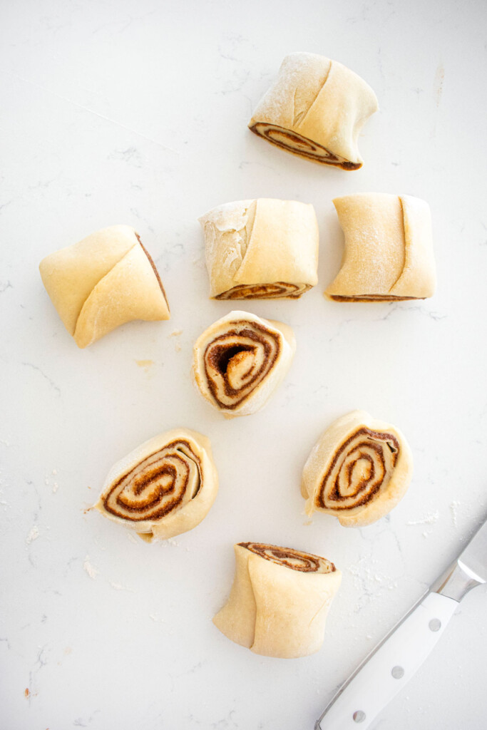 cut cinnamon roll dough on a white marble counter.