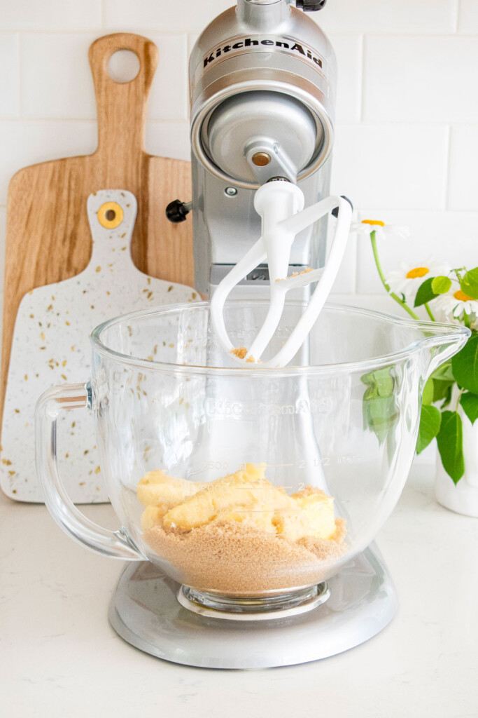 creamed butter and banana chunks in a glass mixing bowl on a white marble counter.