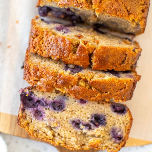 blueberry buttermilk banana bread sliced on a wood cutting board.