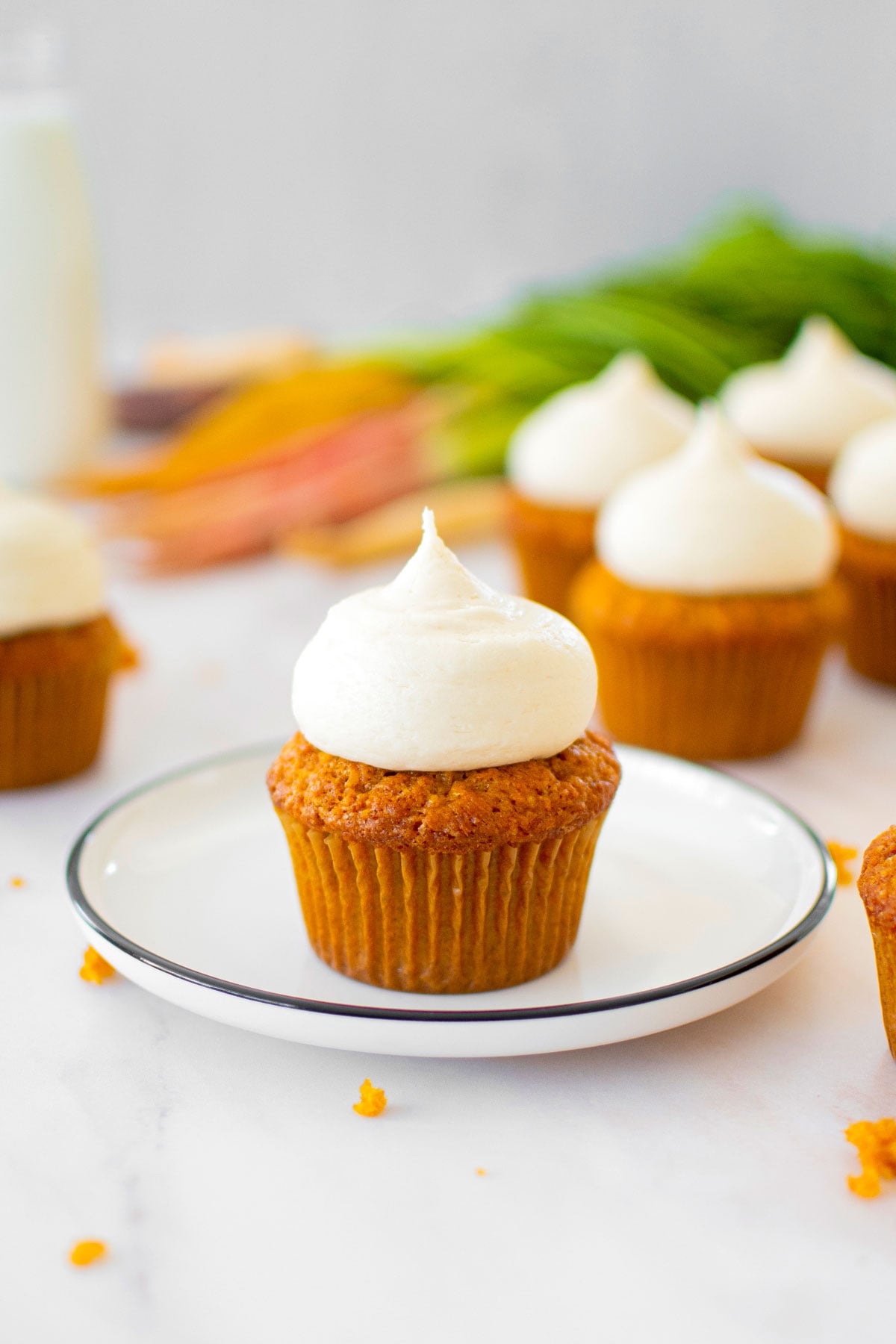 brown sugar carrot cupcake with cream cheese frosting on a plate.