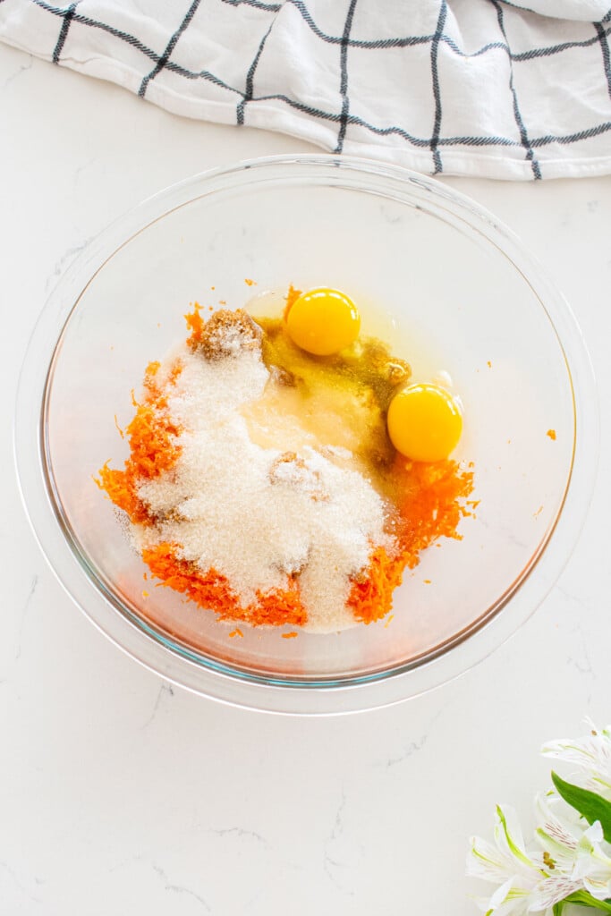 wet ingredients for brown sugar carrot cupcakes in a glass mixing bowl on a white marble counter.