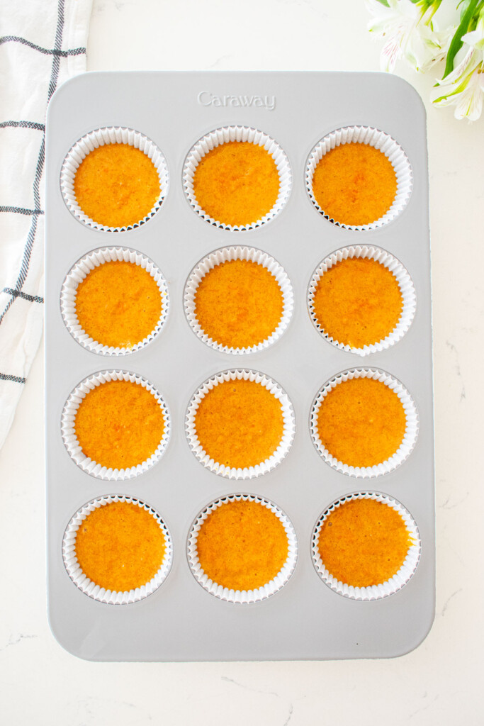 cupcake pan with brown sugar carrot cupcake batter on a white marble counter.