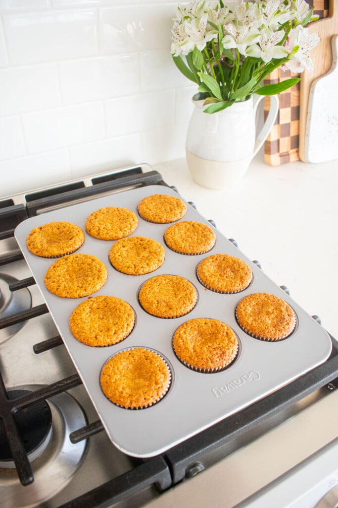 baked brown sugar carrot cupcakes in a cupcake pan on top of a stovetop.