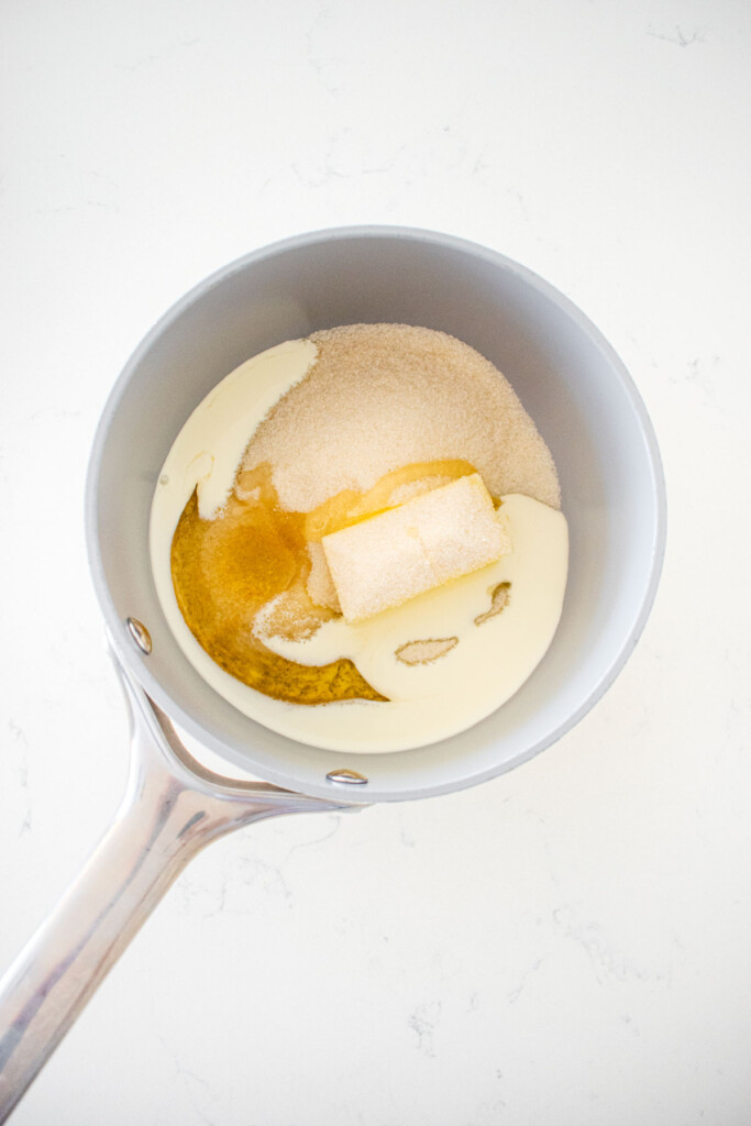 pot with butter, cane sugar, corn syrup and cream on a marble counter.