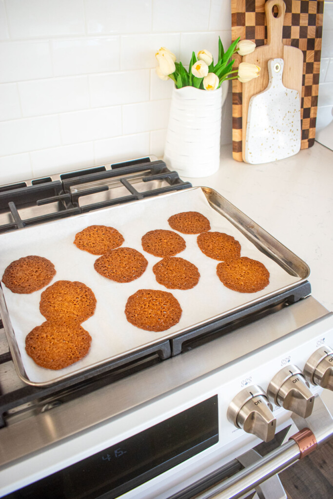 baked florentine cookies cooling on a baking sheet on top of an oven.