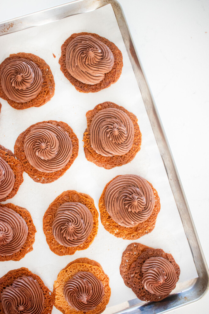 florentine cookies with piped chocolate peanut butter frosting on a baking sheet on a marble counter.