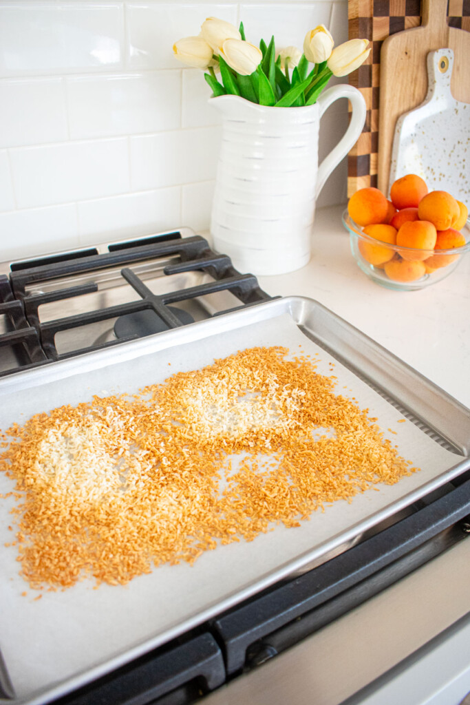 toasted coconut on a baking sheet on top of an oven.
