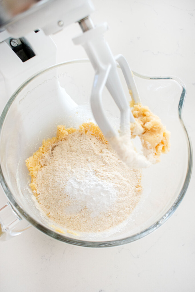 ingredients for snickerdoodle biscotti in a glass mixing bowl on a white marble counter.