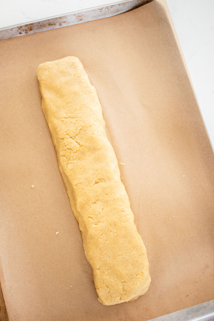cookie dough log formed on a baking sheet with parchment paper.